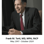Man in suit smiling at desk
